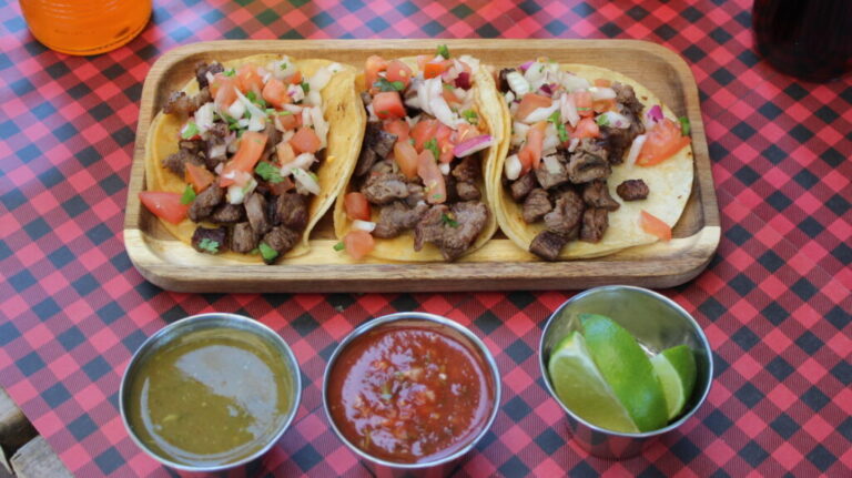 Three street tacos topped with fresh cilantro and served with salsa at Los Tacos Locos